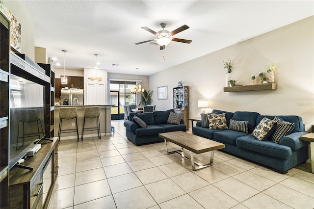 tiled living room with ceiling fan with notable chandelier