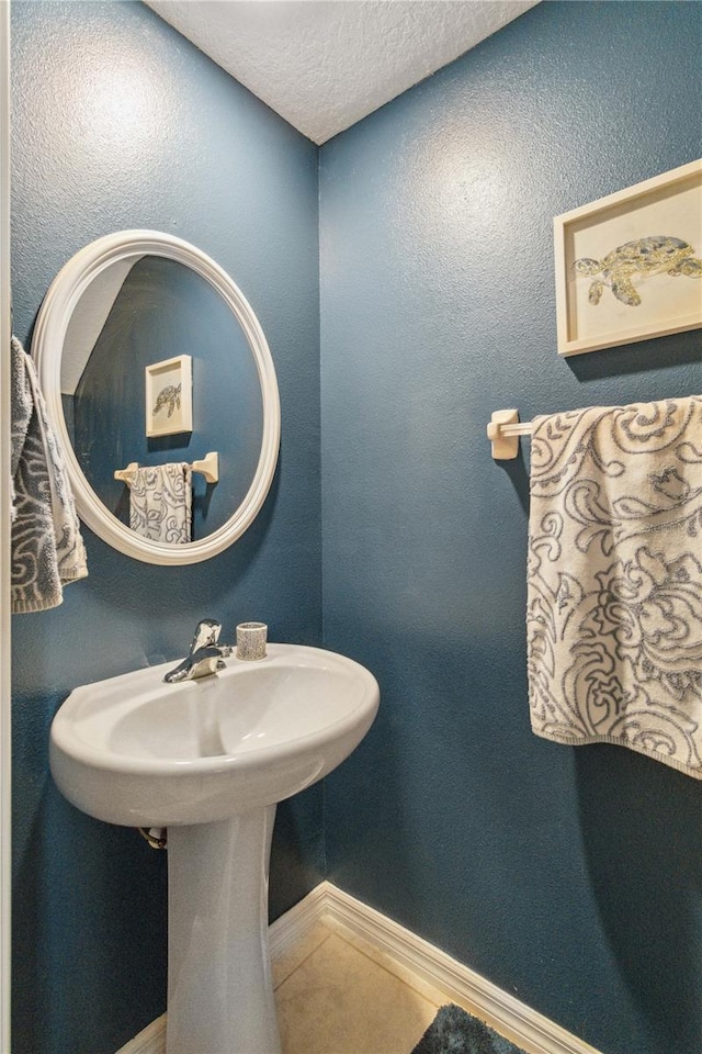 bathroom with a textured ceiling and tile patterned flooring