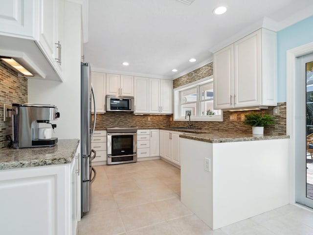 kitchen with white cabinets, sink, dark stone countertops, appliances with stainless steel finishes, and tasteful backsplash