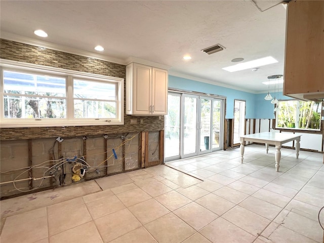 kitchen featuring a skylight, backsplash, pendant lighting, light tile patterned floors, and ornamental molding