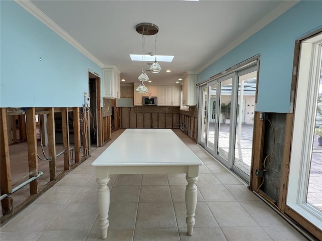 unfurnished dining area featuring light tile patterned floors, a skylight, and ornamental molding