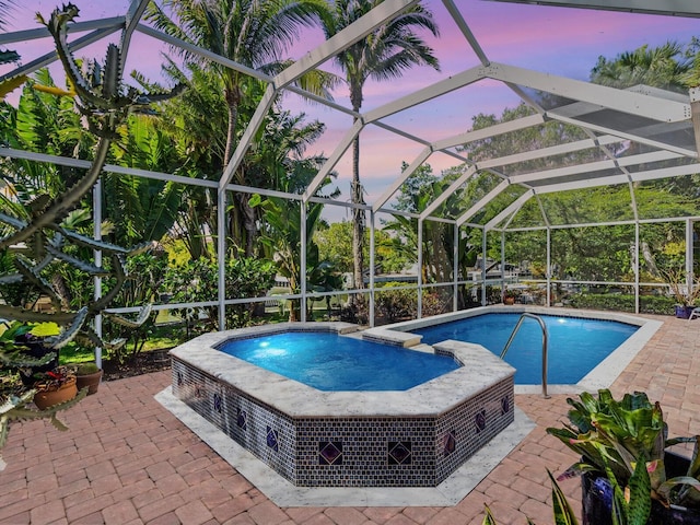 pool at dusk featuring a patio area and a lanai