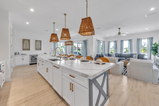 kitchen featuring white cabinetry, sink, ceiling fan, wine cooler, and a kitchen island with sink