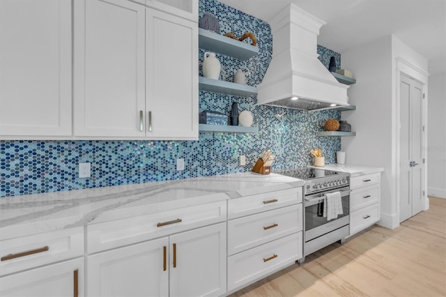 kitchen with premium range hood, light stone counters, tasteful backsplash, white cabinets, and stainless steel range with electric cooktop