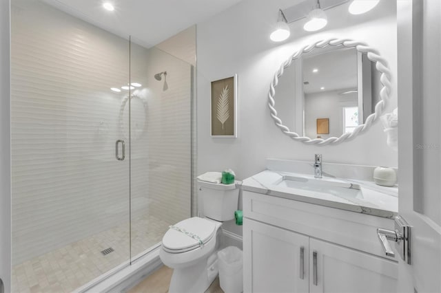 bathroom featuring a shower with door, vanity, and toilet