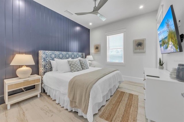 bedroom featuring ceiling fan, wooden walls, and light wood-type flooring