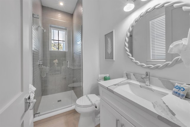 bathroom featuring tile patterned flooring, a shower with door, vanity, and toilet