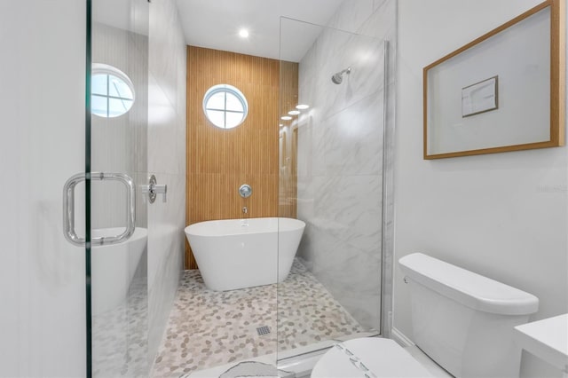 bathroom featuring separate shower and tub, toilet, and tile walls