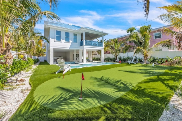 rear view of property featuring a balcony and a fenced in pool