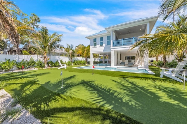 back of property featuring a balcony, ceiling fan, and a fenced in pool