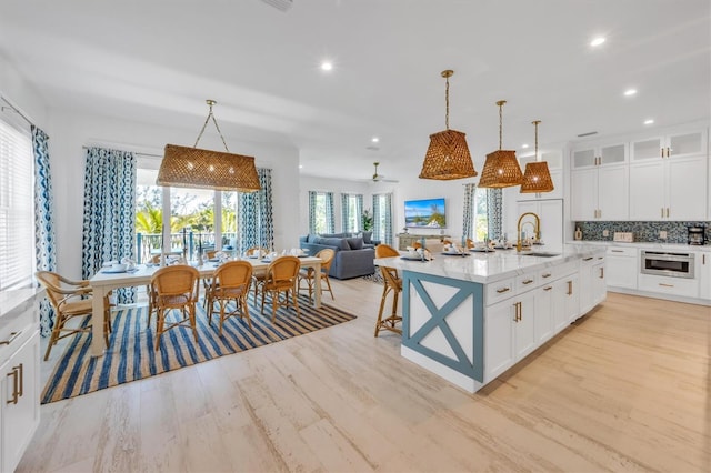 kitchen with a center island with sink, decorative backsplash, ceiling fan, and hanging light fixtures