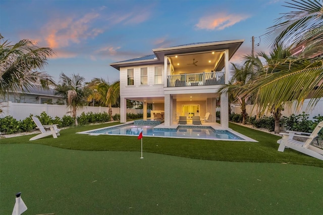 back house at dusk featuring ceiling fan, a pool with hot tub, a balcony, and a patio area