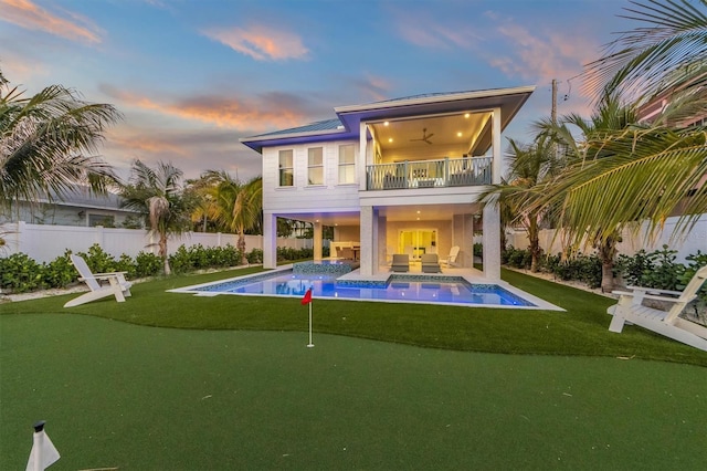 back house at dusk with a swimming pool with hot tub, a patio, a balcony, and ceiling fan