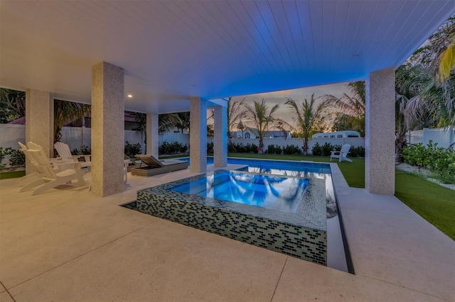 pool at dusk featuring a yard and a patio