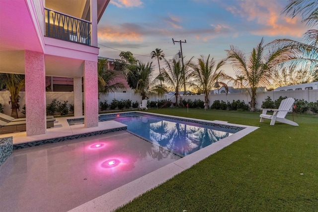 pool at dusk with a yard and a patio