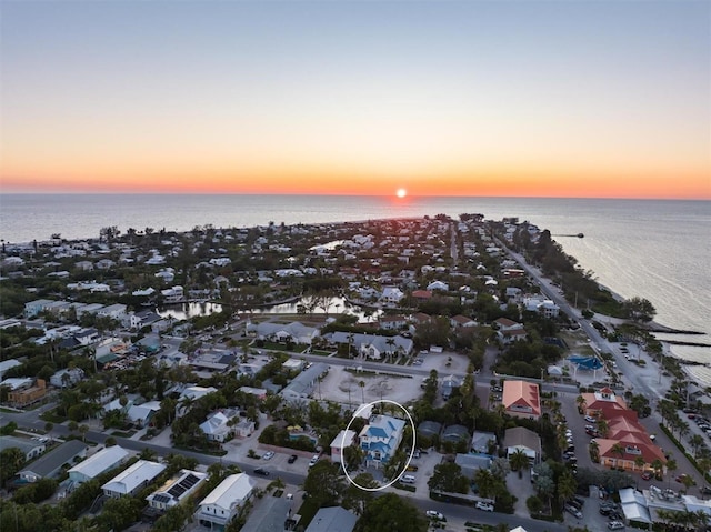 aerial view at dusk featuring a water view