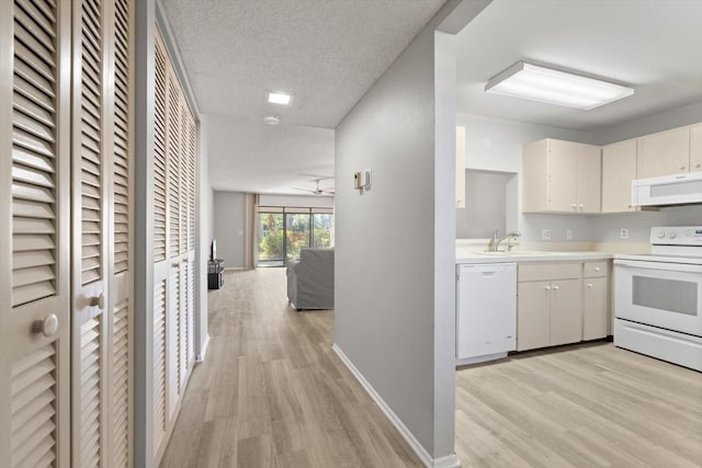 kitchen with sink, white appliances, light hardwood / wood-style flooring, white cabinets, and a textured ceiling