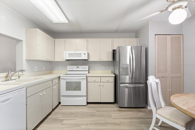 kitchen featuring ceiling fan, white appliances, sink, and light hardwood / wood-style flooring