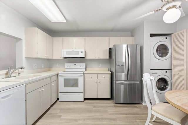 kitchen with stacked washer and dryer, sink, white appliances, and light hardwood / wood-style flooring