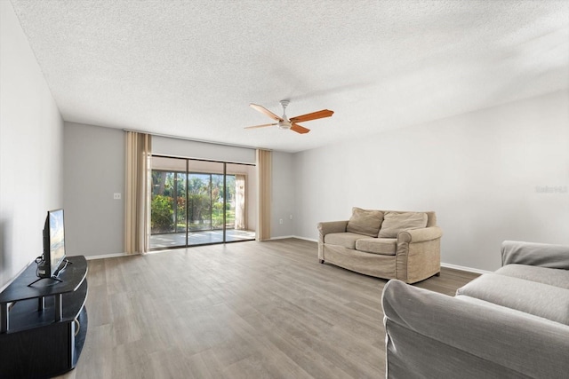 living room with hardwood / wood-style flooring, ceiling fan, and a textured ceiling