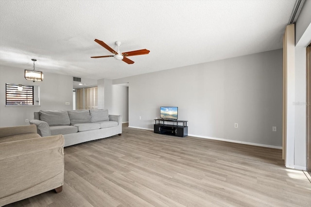 living room with ceiling fan, a textured ceiling, and light wood-type flooring