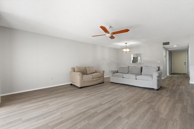 living room with wood-type flooring, ceiling fan with notable chandelier, and a textured ceiling