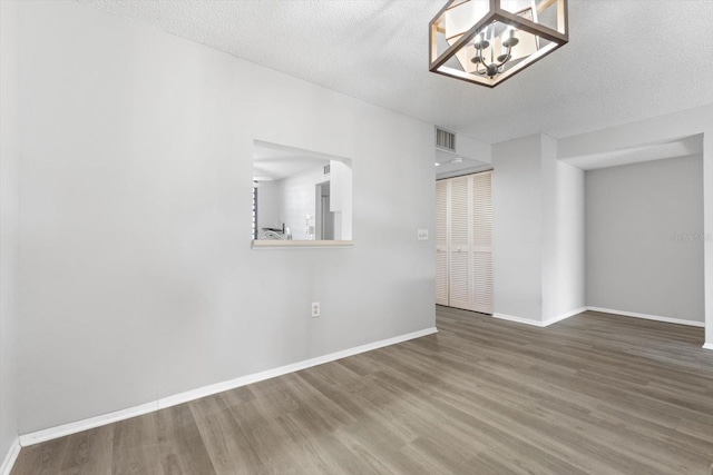 spare room featuring a chandelier, hardwood / wood-style floors, and a textured ceiling