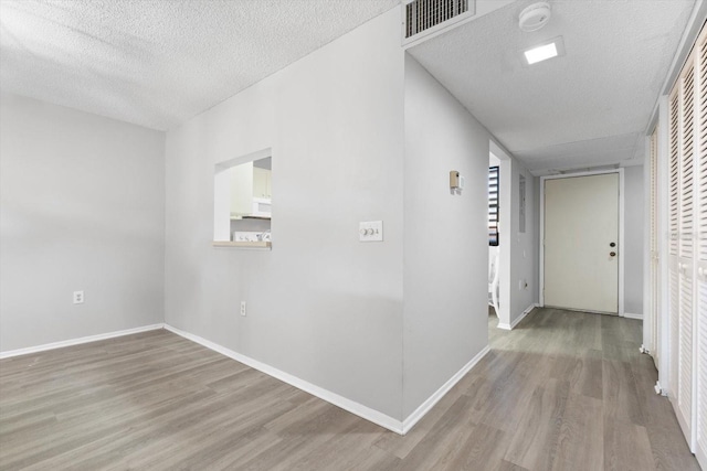 hallway featuring a textured ceiling and light hardwood / wood-style flooring