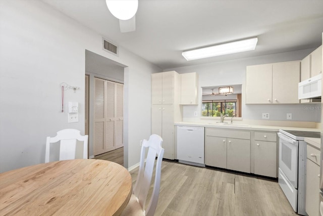 kitchen featuring white cabinetry, sink, white appliances, and light hardwood / wood-style flooring