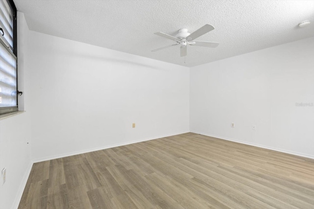 empty room with ceiling fan, light hardwood / wood-style floors, and a textured ceiling