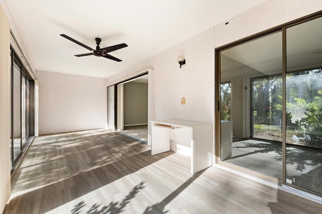 interior space featuring hardwood / wood-style flooring, built in desk, and ceiling fan