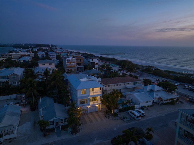 aerial view at dusk with a water view and a view of the beach