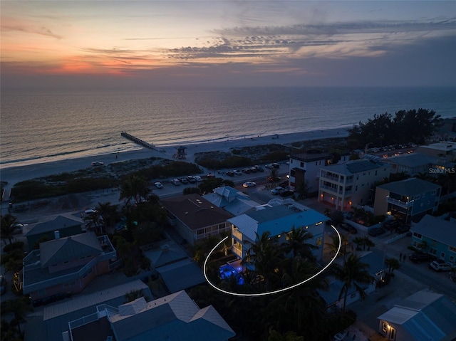 aerial view at dusk with a water view and a view of the beach