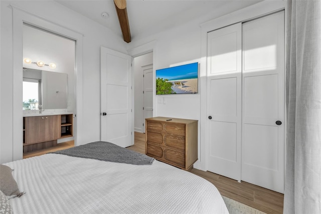 bedroom featuring beamed ceiling, wood-type flooring, a closet, and ceiling fan