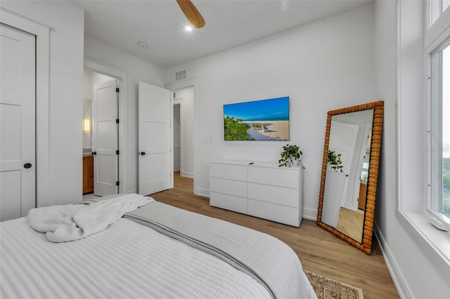 bedroom featuring ceiling fan, light wood-type flooring, and multiple windows