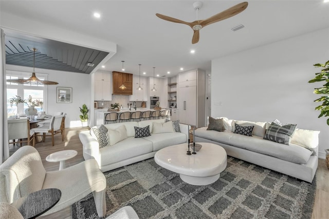 living room featuring hardwood / wood-style floors, ceiling fan, and sink