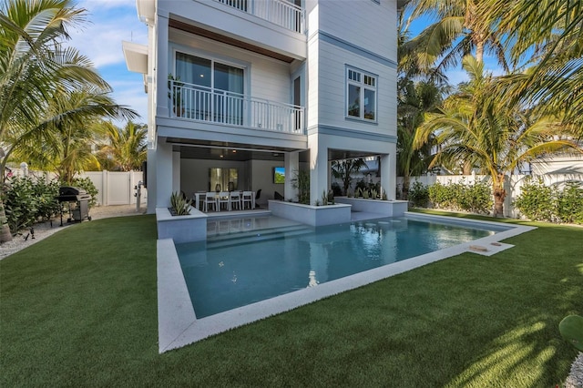 back of property with a fenced in pool, a patio area, a balcony, and a yard