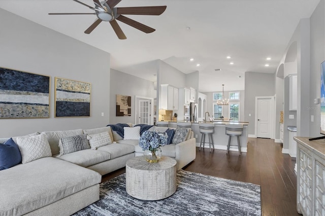 living room featuring high vaulted ceiling, dark hardwood / wood-style floors, sink, and ceiling fan with notable chandelier