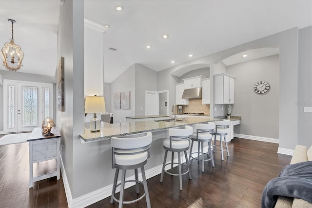 kitchen featuring white cabinetry, kitchen peninsula, a breakfast bar area, decorative backsplash, and sink