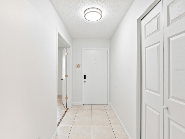 doorway featuring light tile patterned flooring and a textured ceiling