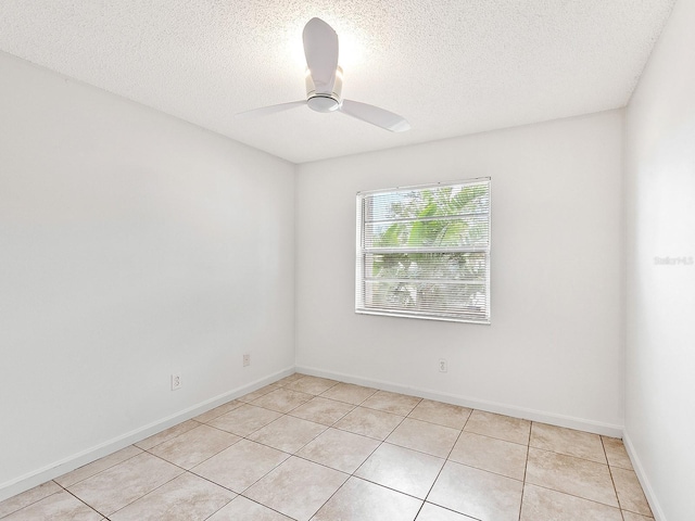 spare room featuring ceiling fan, light tile patterned floors, and a textured ceiling