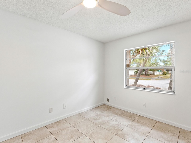 tiled empty room with ceiling fan and a textured ceiling