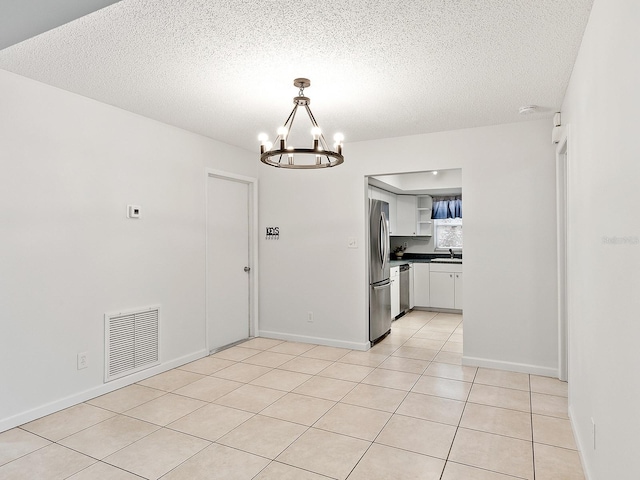 kitchen featuring stainless steel appliances, decorative light fixtures, a notable chandelier, white cabinetry, and light tile patterned flooring