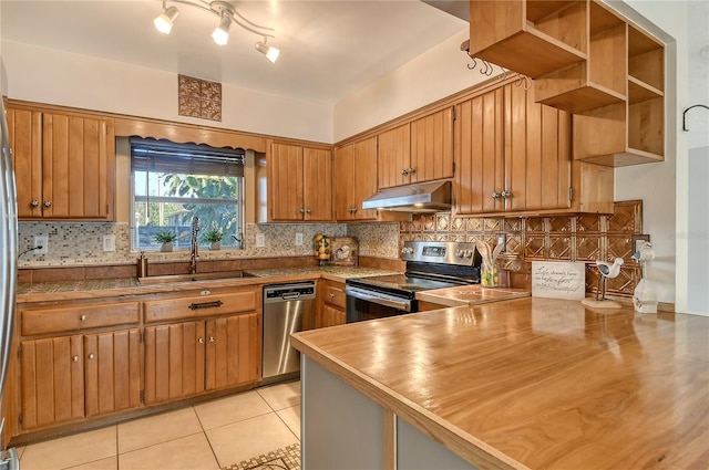 kitchen with kitchen peninsula, appliances with stainless steel finishes, decorative backsplash, sink, and light tile patterned floors