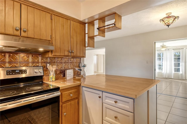 kitchen featuring stainless steel electric range oven, ceiling fan, tasteful backsplash, kitchen peninsula, and light tile patterned flooring