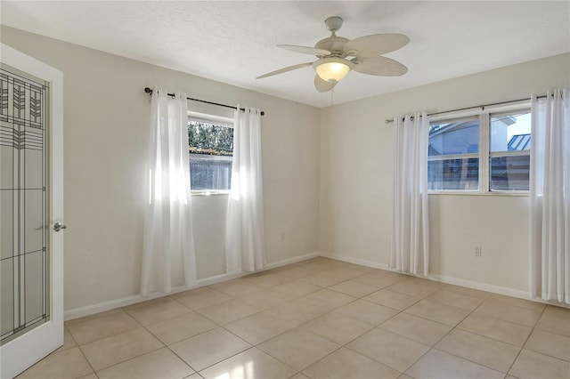 tiled empty room with ceiling fan and a textured ceiling