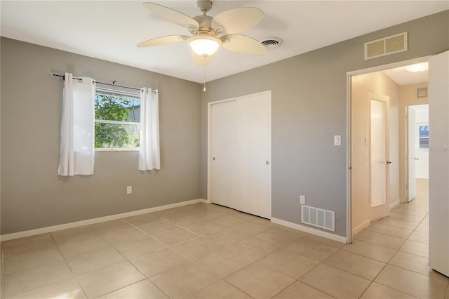 unfurnished bedroom with ceiling fan, light tile patterned flooring, and a closet