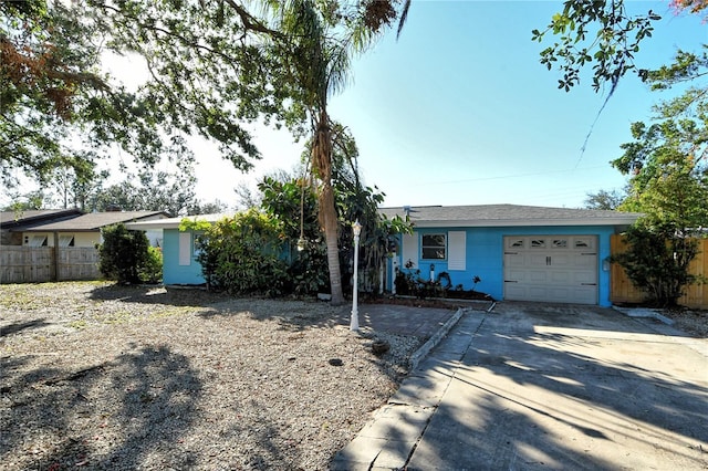 ranch-style home with a garage, driveway, and fence