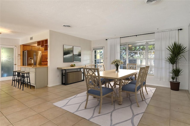 dining space with visible vents, a textured ceiling, and light tile patterned flooring