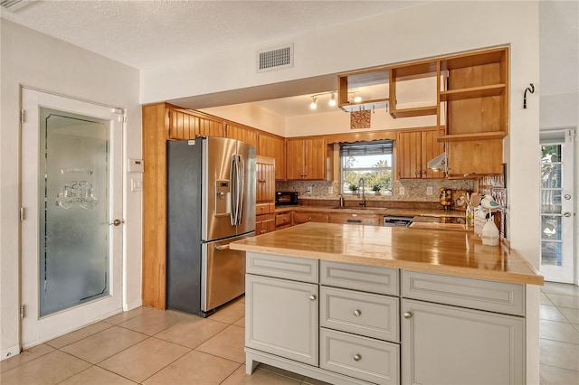 kitchen with butcher block counters, visible vents, appliances with stainless steel finishes, backsplash, and brown cabinetry